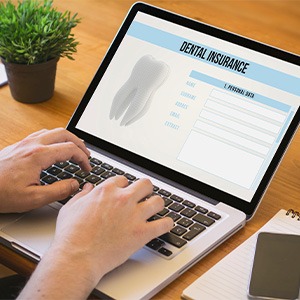 Patient filling out dental insurance information on laptop