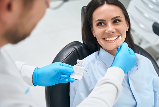 A dentist using a shade guide to determine color of prepless veneers