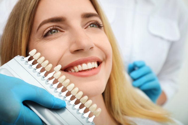 woman smiling while dentist uses shade guide